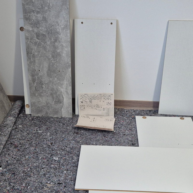 Lesnina omara za čevlje v belo sivi barvi pred sestavo