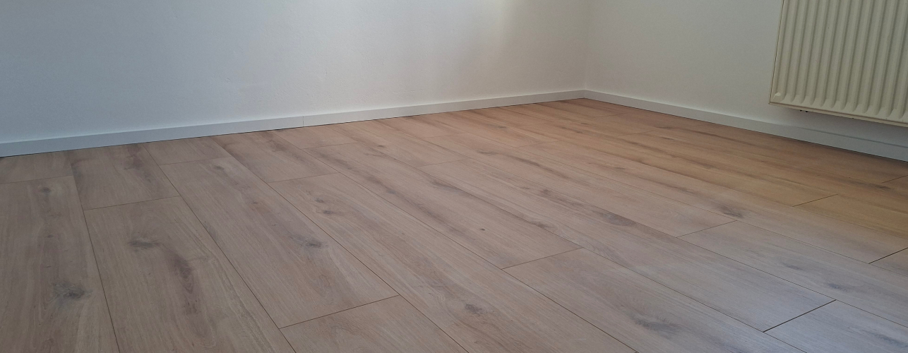 Zaključeno polaganje rustikalnega laminata z elegantnimi belimi zaključnimi letvicami v prenovljeni hiši